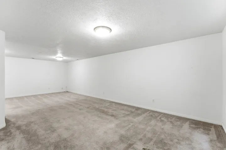 Spacious room featuring neutral carpeting and white walls