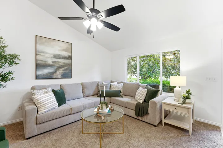 Living area featuring a vaulted ceiling and a ceiling fan with integrated lighting