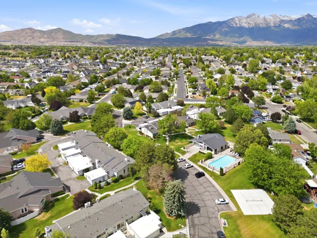 Aerial perspective showcasing a residential community with abundant mature trees and mountainous terrain in the background