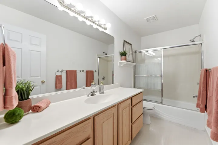 Full-width vanity with a single basin sink, light-toned countertop, and wood-finish cabinetry