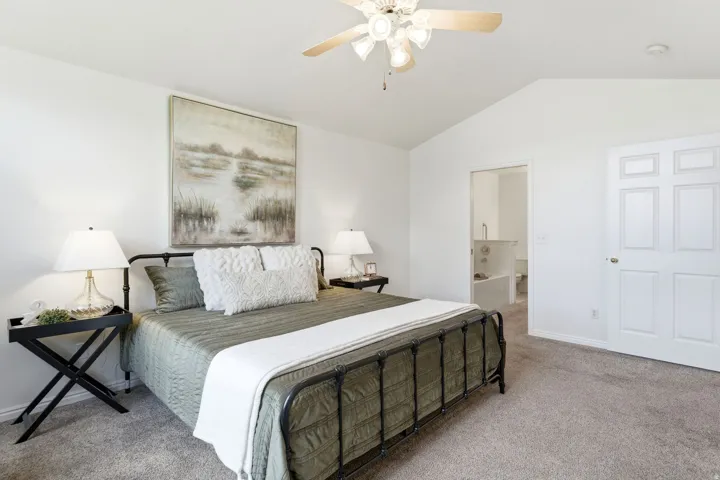 Carpeted bedroom with vaulted ceilings, a ceiling fan, and white painted walls