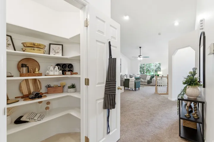 Walk-in pantry featuring white shelving and a paneled door