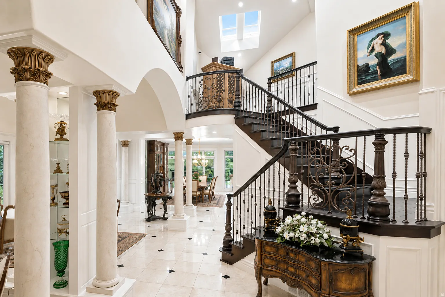 Grand foyer featuring a dual staircase with intricate iron balusters and dark wood handrails