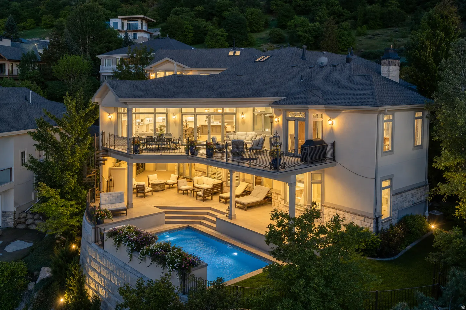 Multi-level residence featuring a stucco exterior with stone accents, a deep blue shingle roof, and a tiered outdoor living space