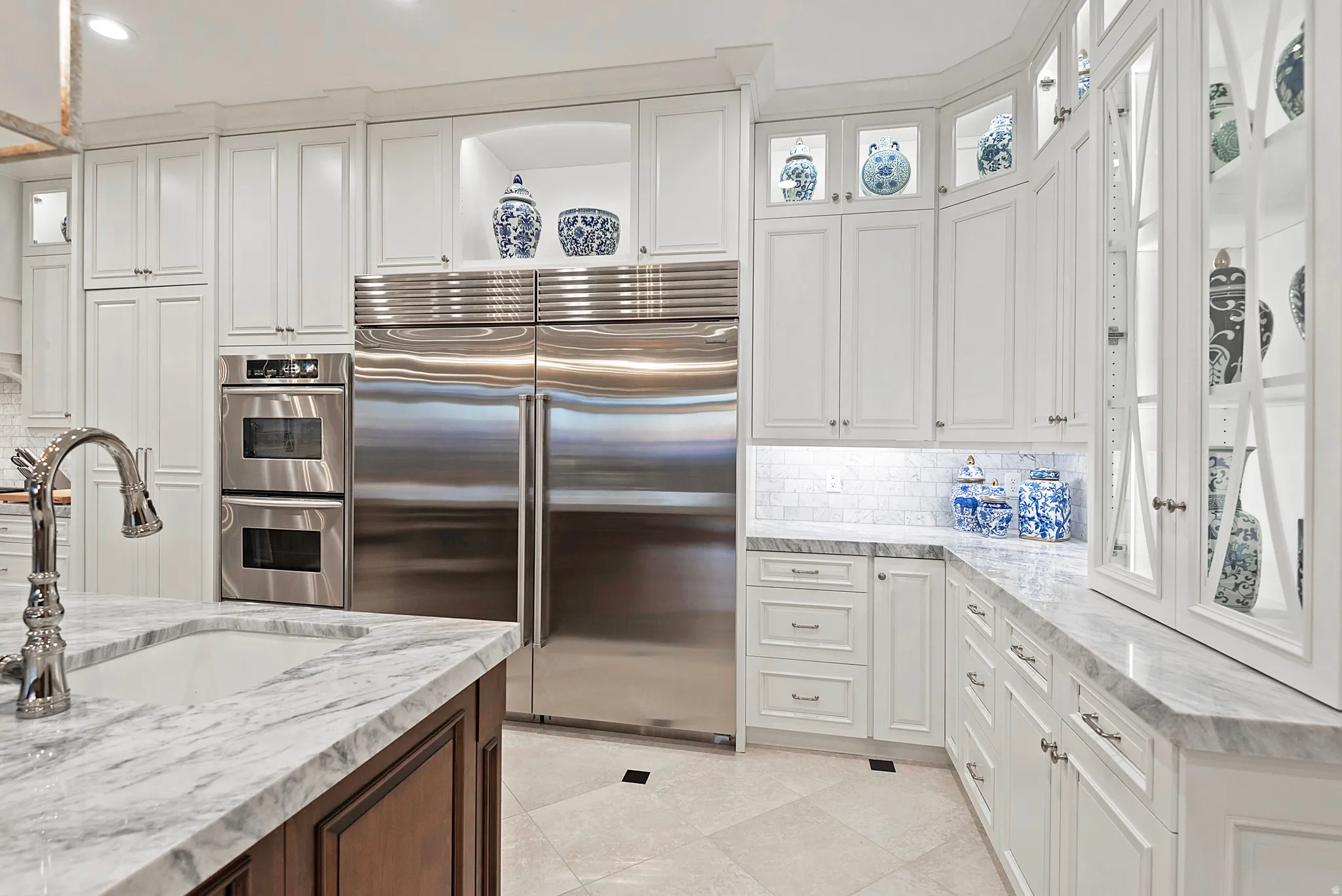 Gourmet kitchen featuring white shaker cabinetry, stainless steel double ovens, integrated refrigerator and freezer, stone countertops, and a subway tile backsplash