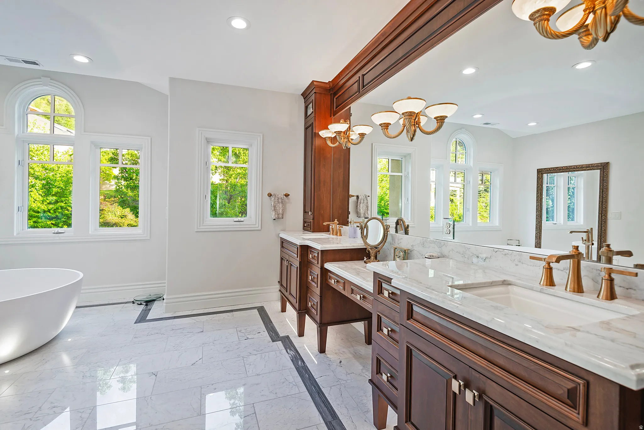 Dual vanity with stone countertops and bronze-tone fixtures, complemented by a large integrated mirror