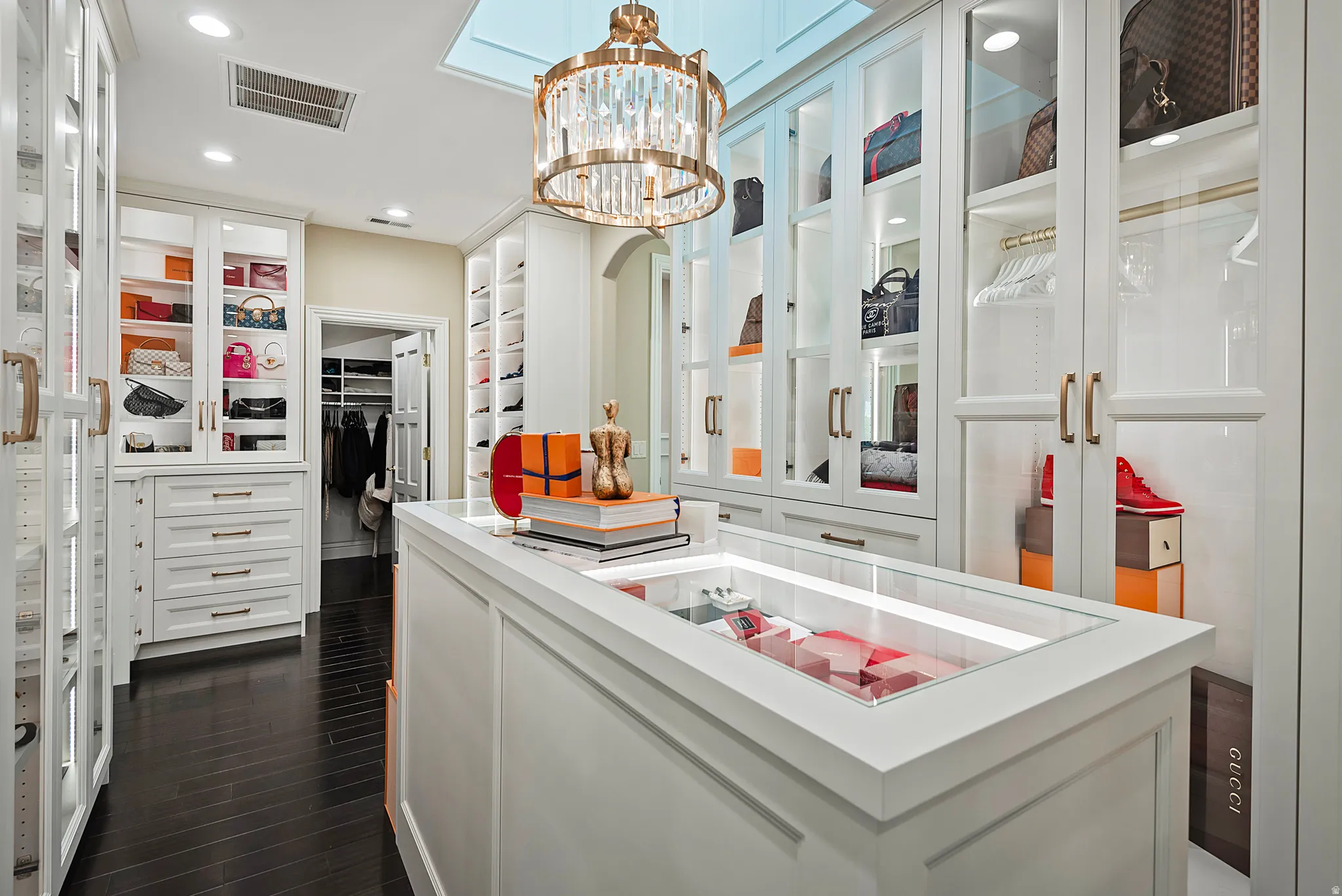 Custom closet featuring dark wood-finish flooring and extensive white cabinetry