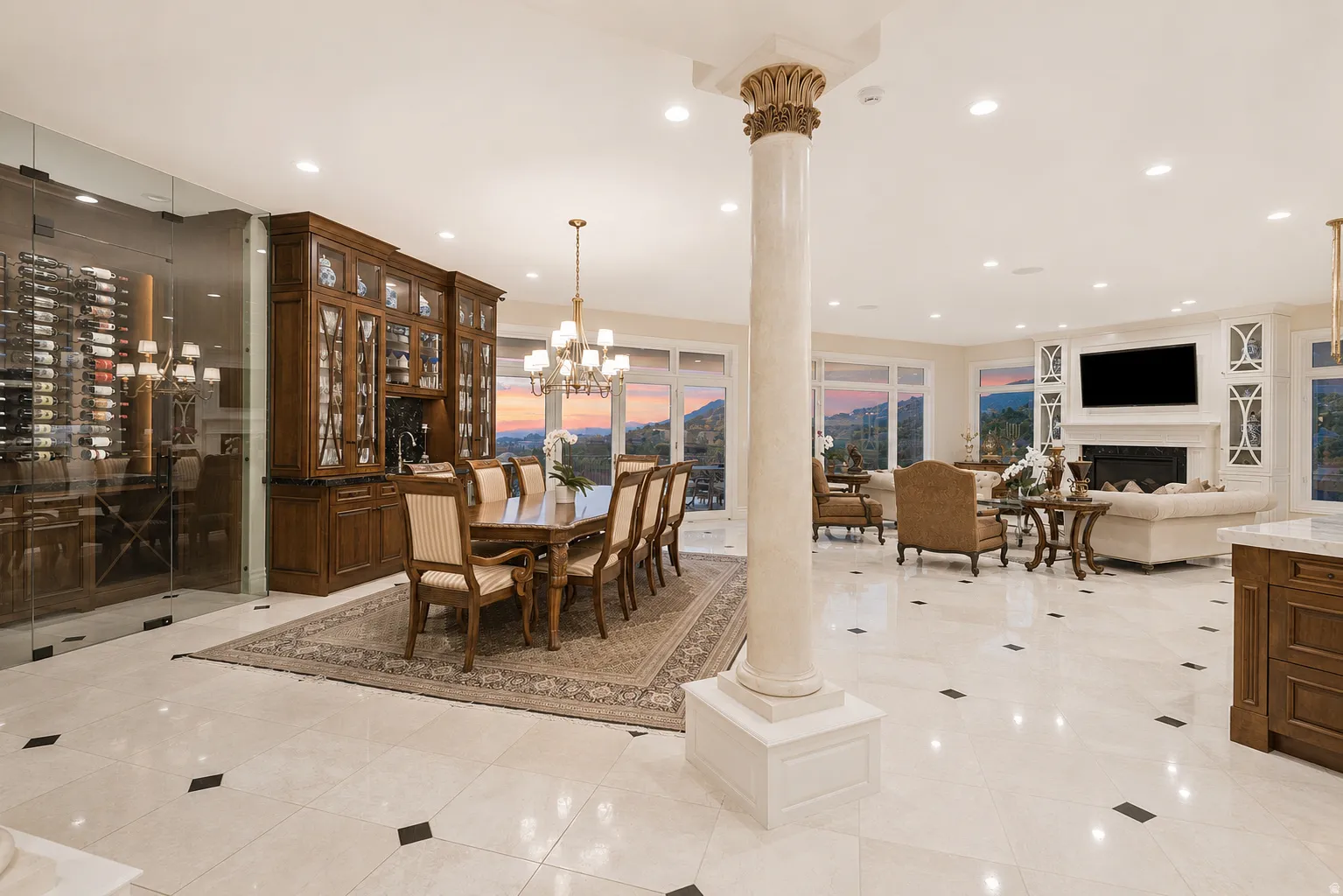 Spacious open-concept living area featuring a built-in wine wall, light-toned tile flooring with dark accents, recessed lighting, a decorative column, and a built-in entertainment center with fireplace