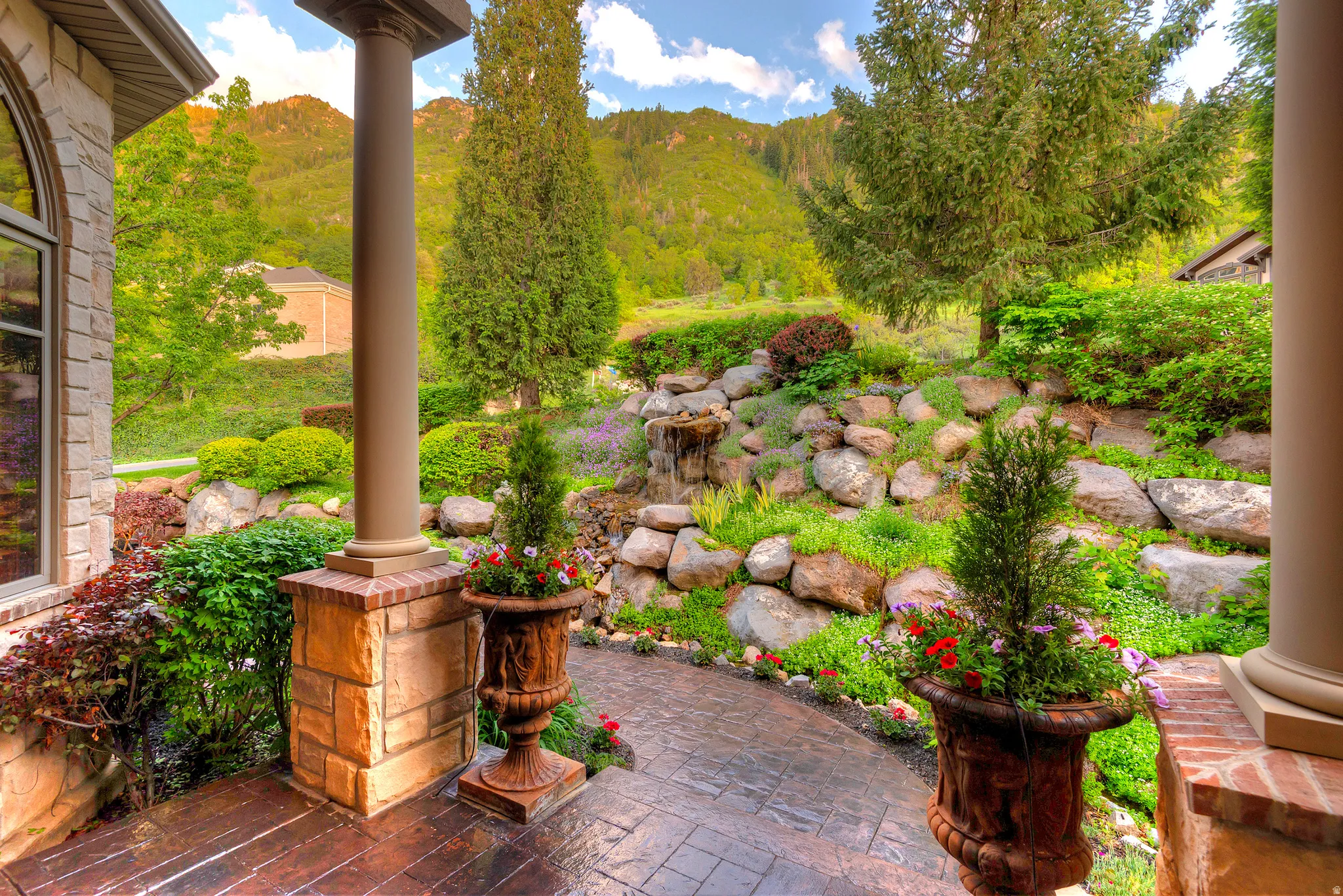 Front patio featuring an arched window, stone and brick column base, and a stamped concrete surface