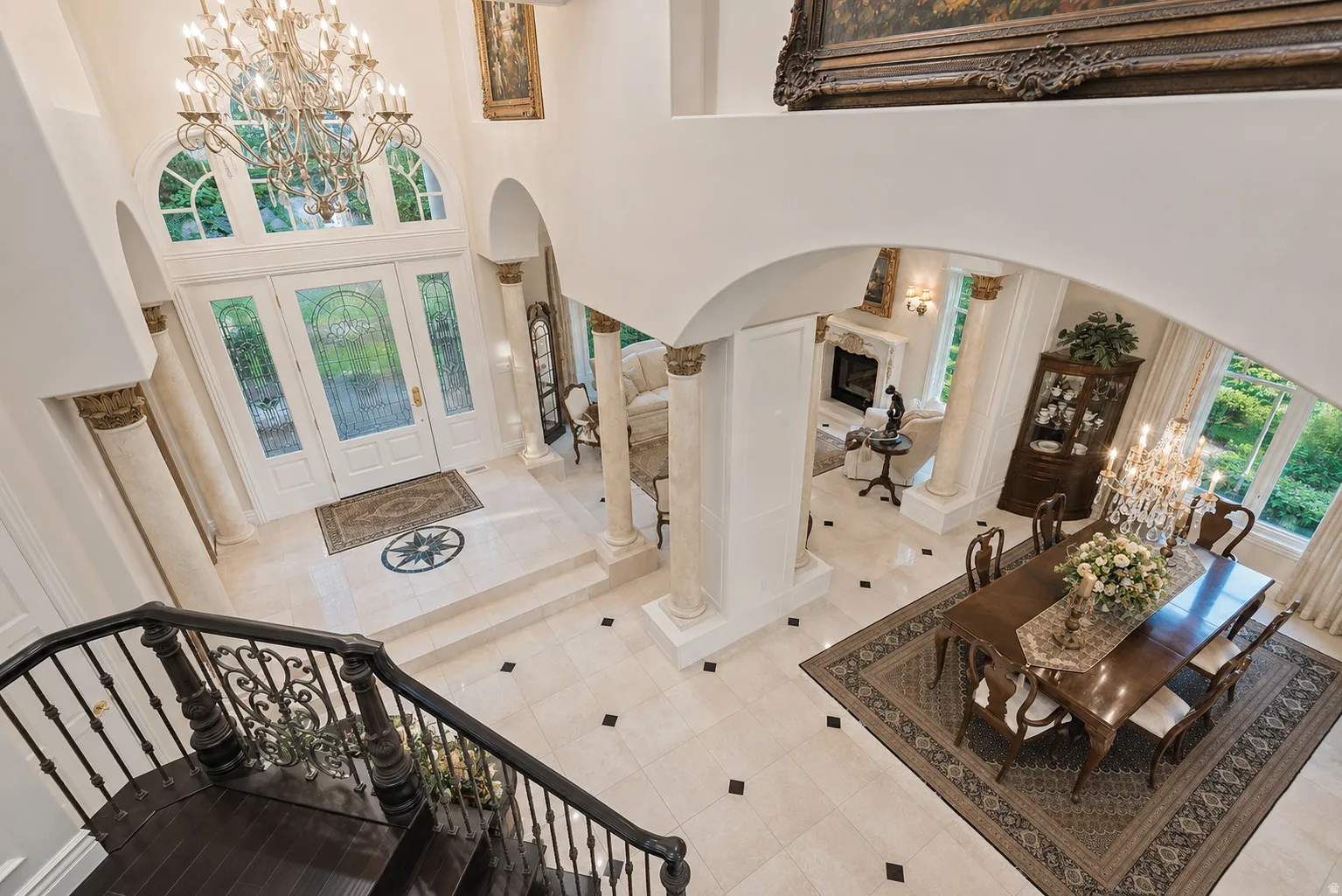 Two-story entryway featuring a decorative glass double-door entrance with transom and sidelights, a large chandelier, and detailed tile flooring