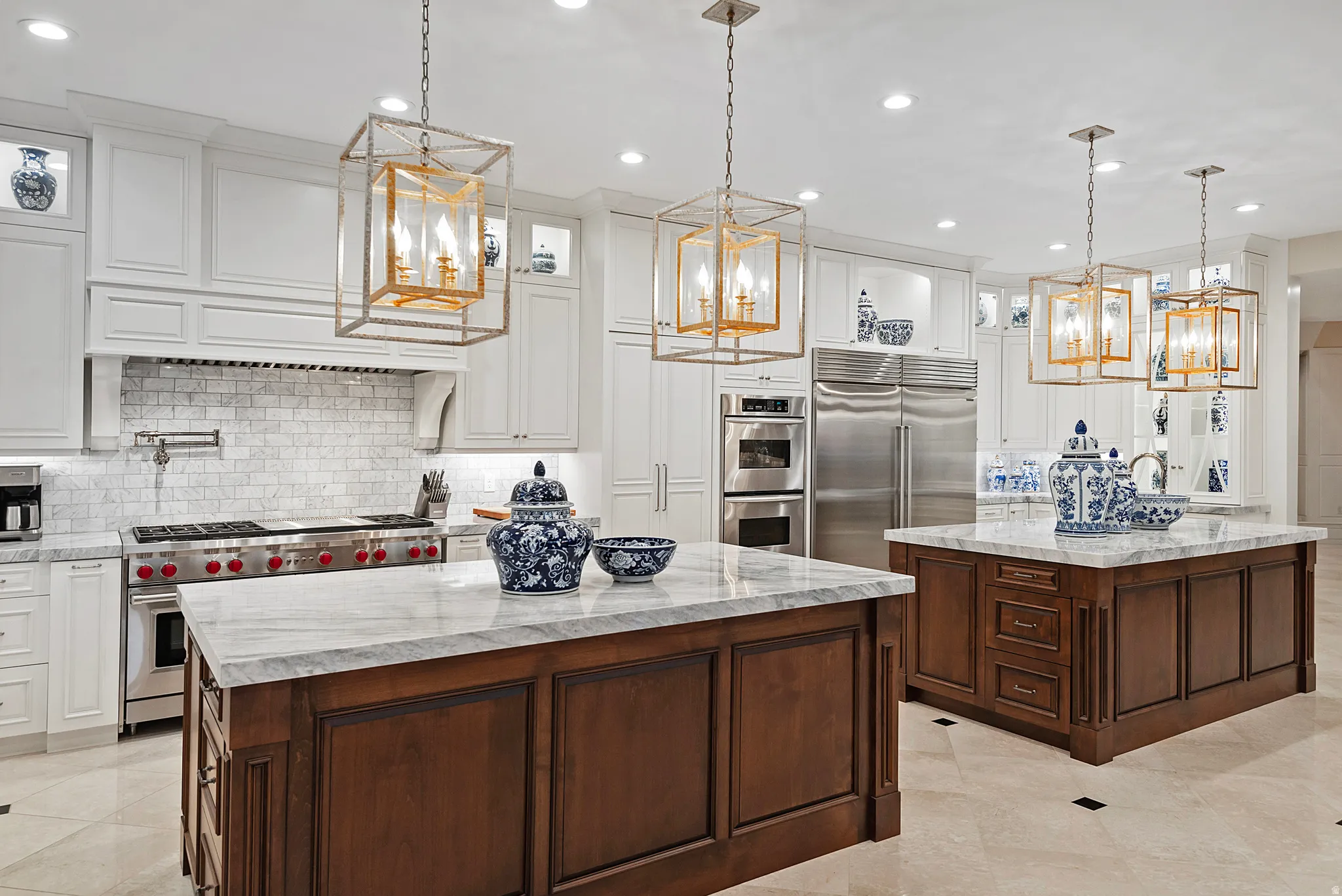 Gourmet kitchen featuring dual islands with stone countertops, a professional-grade range, full-height tile backsplash, and integrated stainless steel appliances