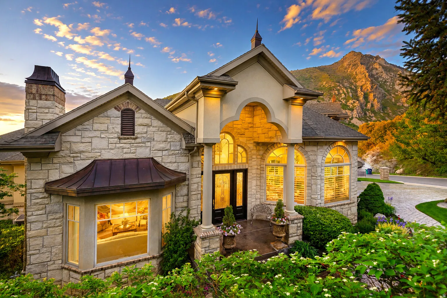 Stone-clad exterior with a prominent arched entry, multiple arched windows, and a bay window featuring a copper roof