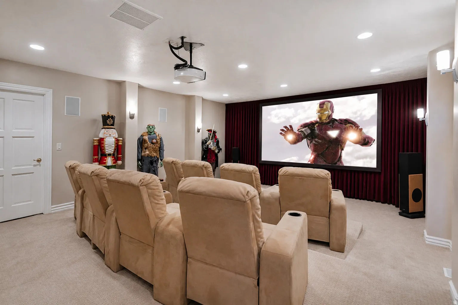 Dedicated home theater featuring a large projection screen, recessed lighting, and wall-mounted sconces