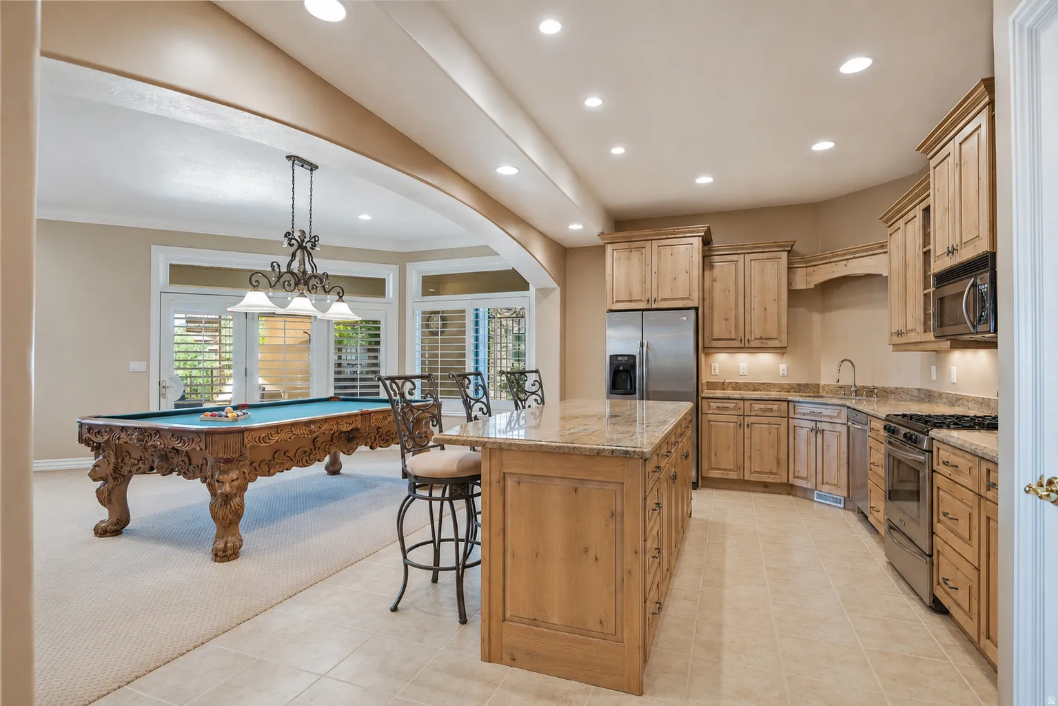 Spacious open-concept area featuring a kitchen with an island, light wood cabinetry, and stainless steel appliances