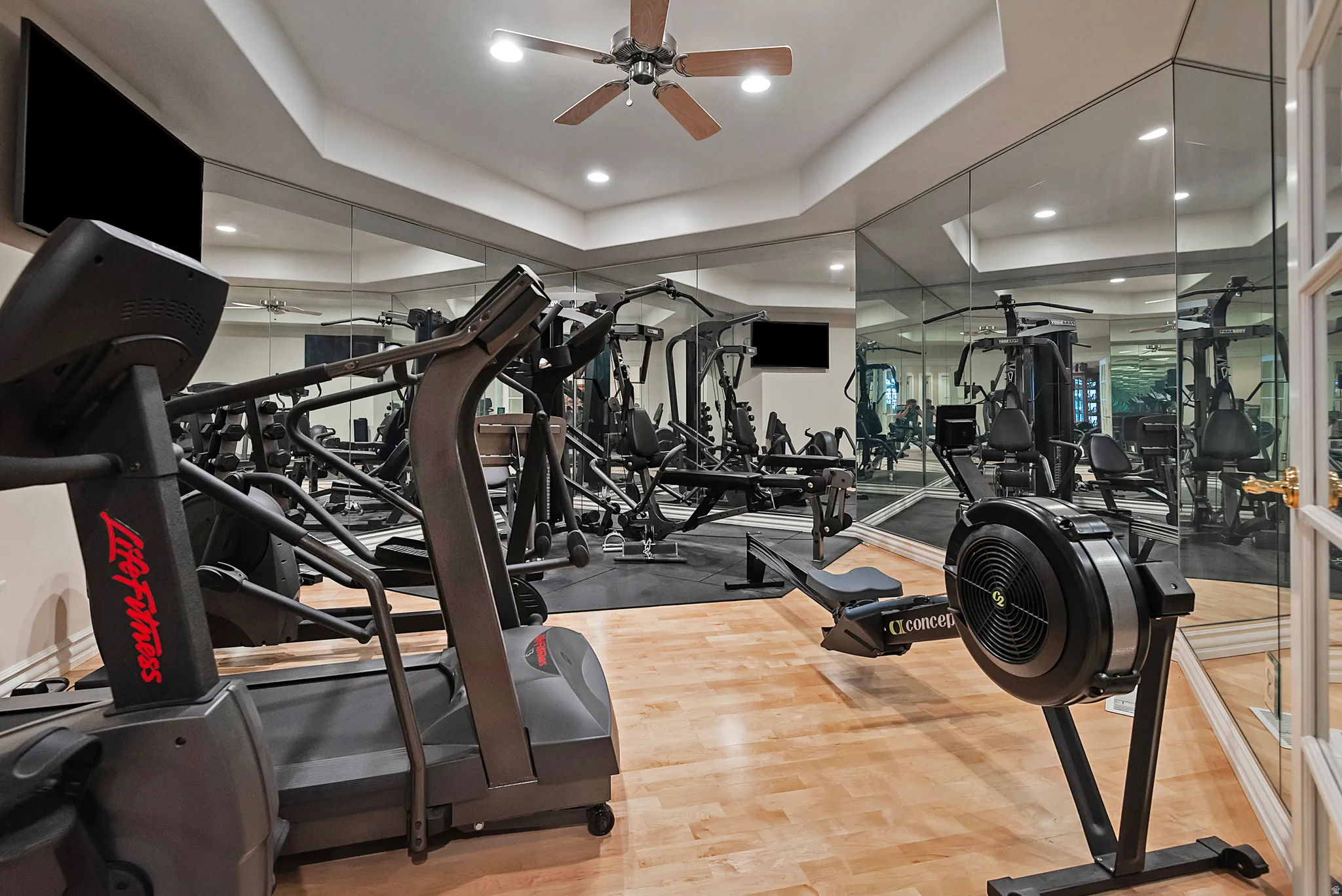 Dedicated fitness space with wood-finish flooring and mirrored walls
