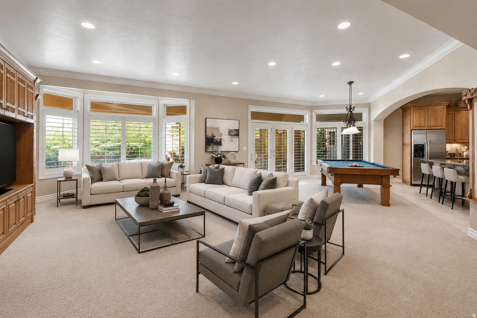 Open-concept living area with extensive bay windows, crown molding, recessed lighting, and built-in cabinetry