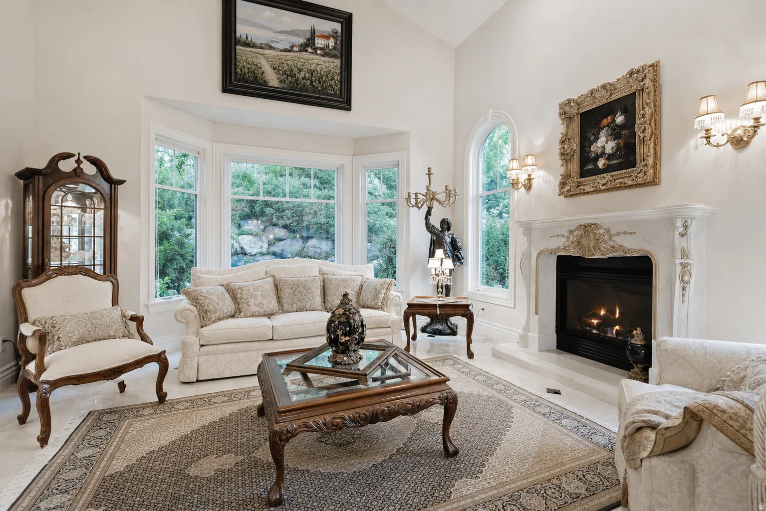 Grand living space featuring a highly detailed fireplace with a mantel, ornate wall sconces, large bay windows, and an arched window