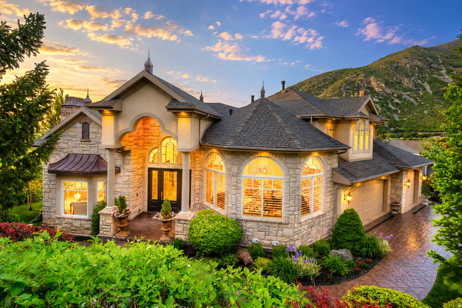 Stone facade residence featuring multiple dormers, arched entryway, and bay windows