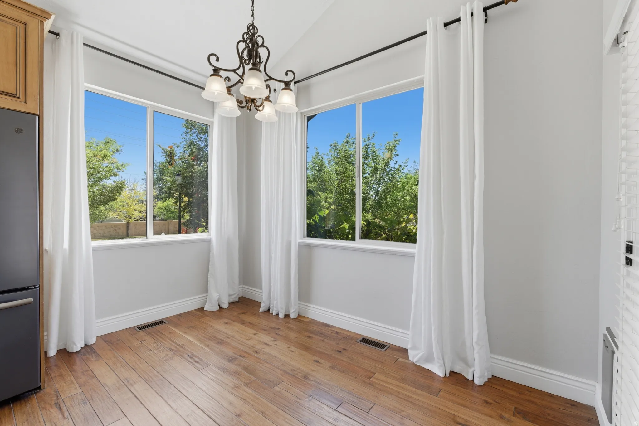 Dining area featuring three large windows, a decorative chandelier, and wood-finish flooring