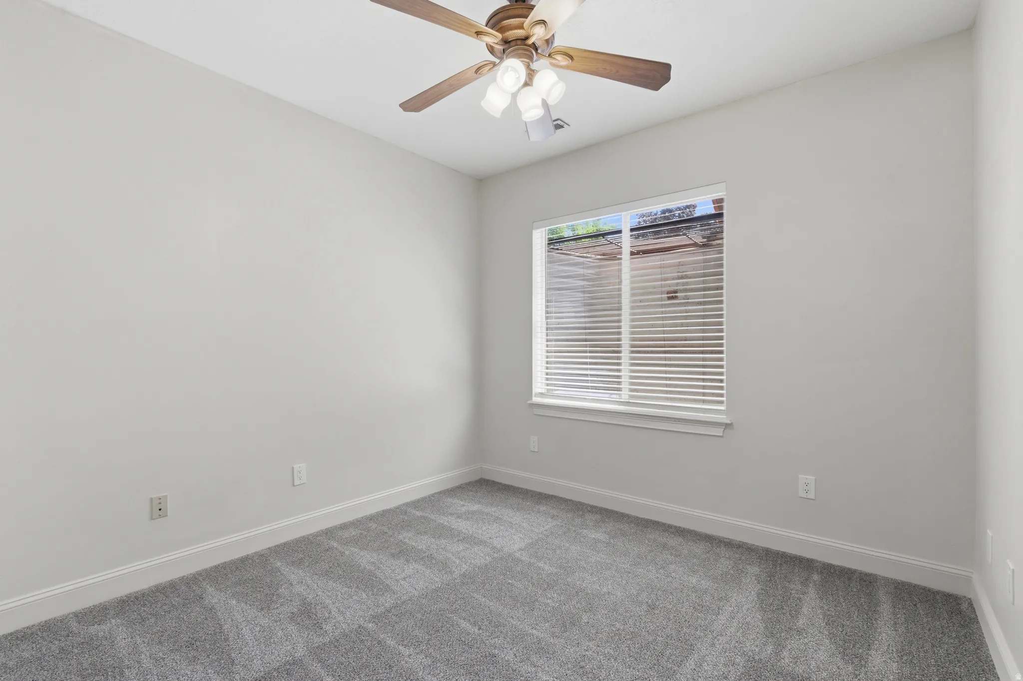 Bedroom featuring light gray wall paint, gray patterned carpeting, white baseboards, and a window with white blinds