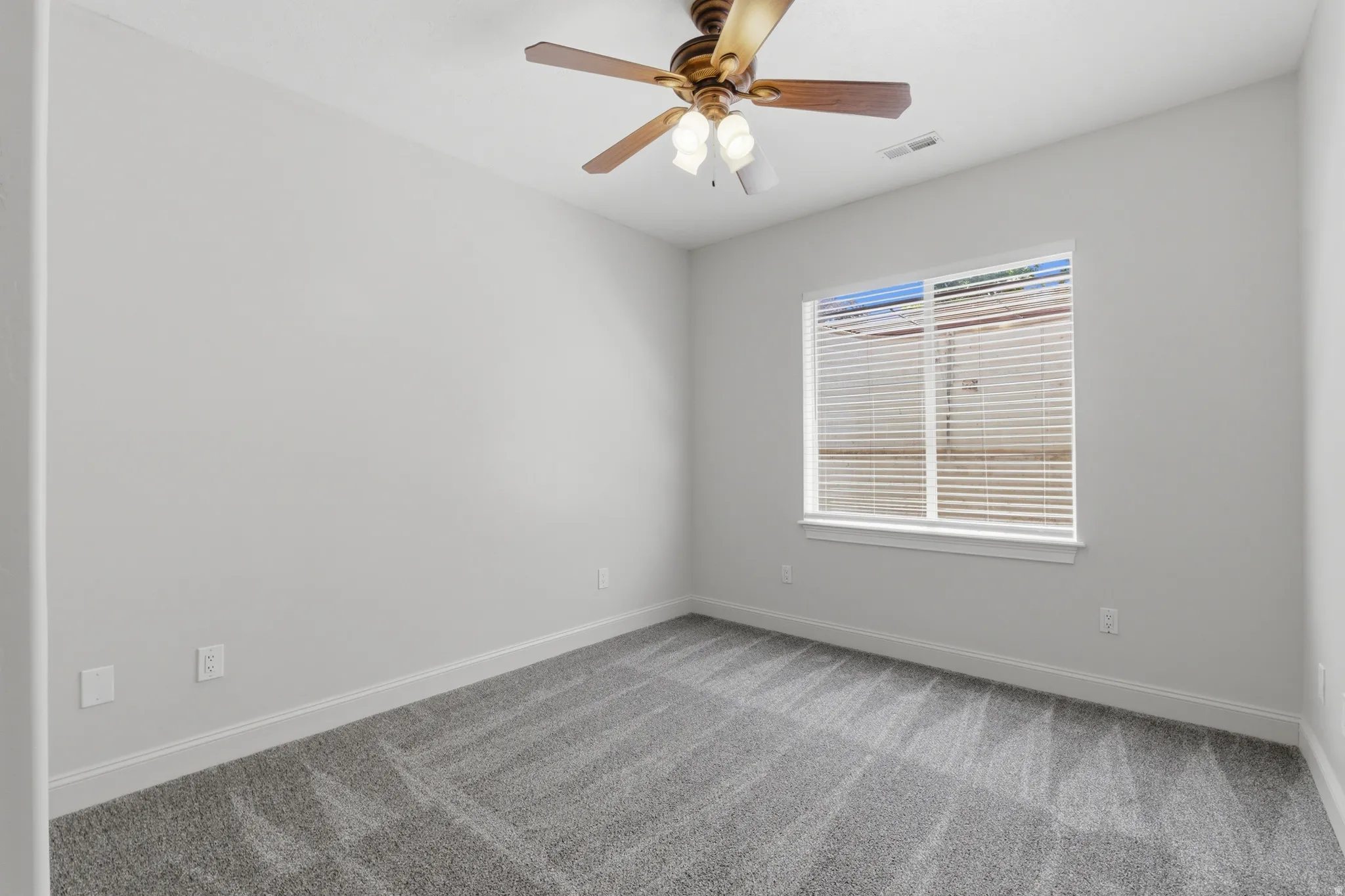 Room featuring light gray walls, gray patterned carpet, and white baseboards