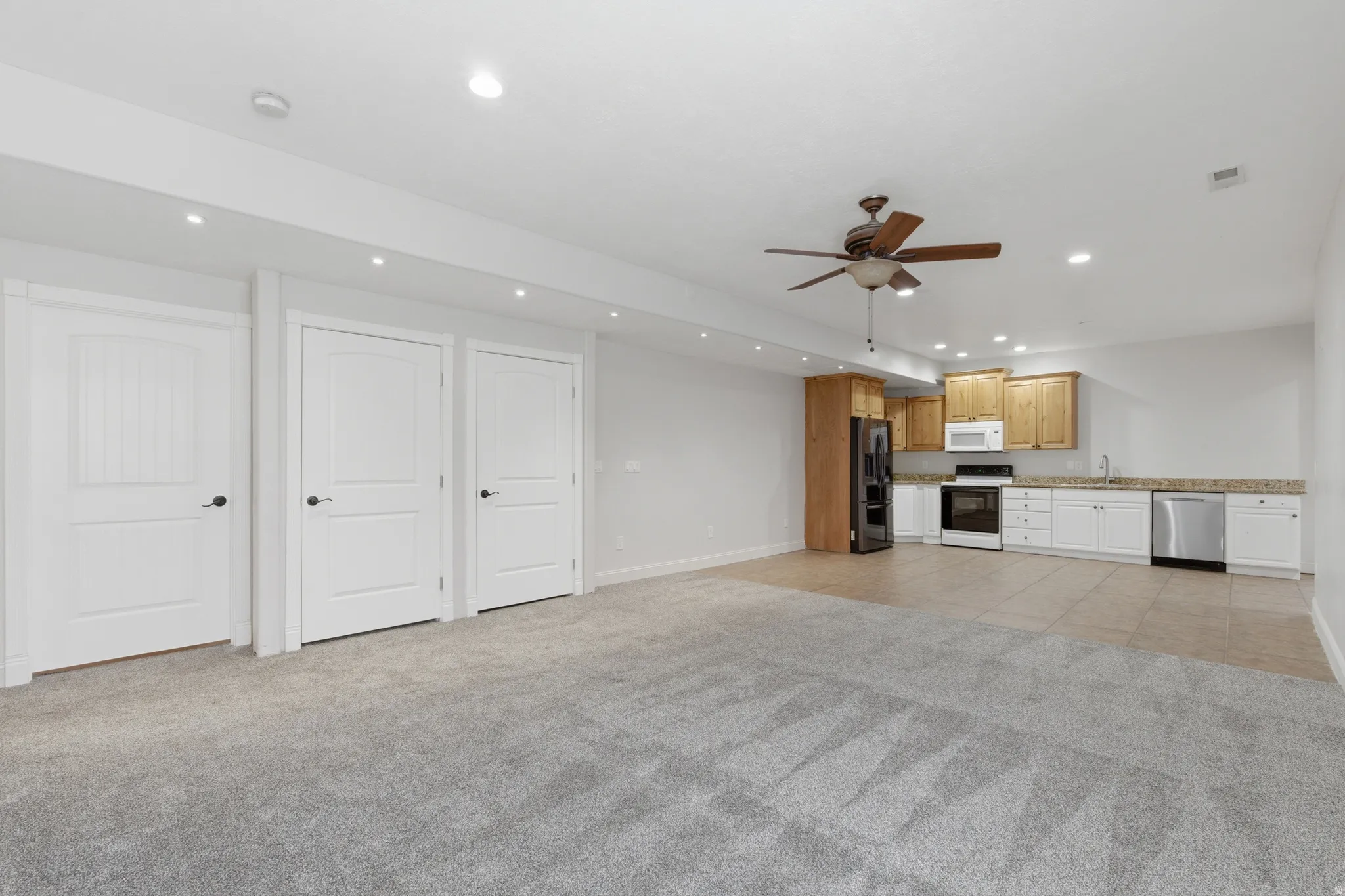 Open concept room with gray carpeting and a full kitchen area
