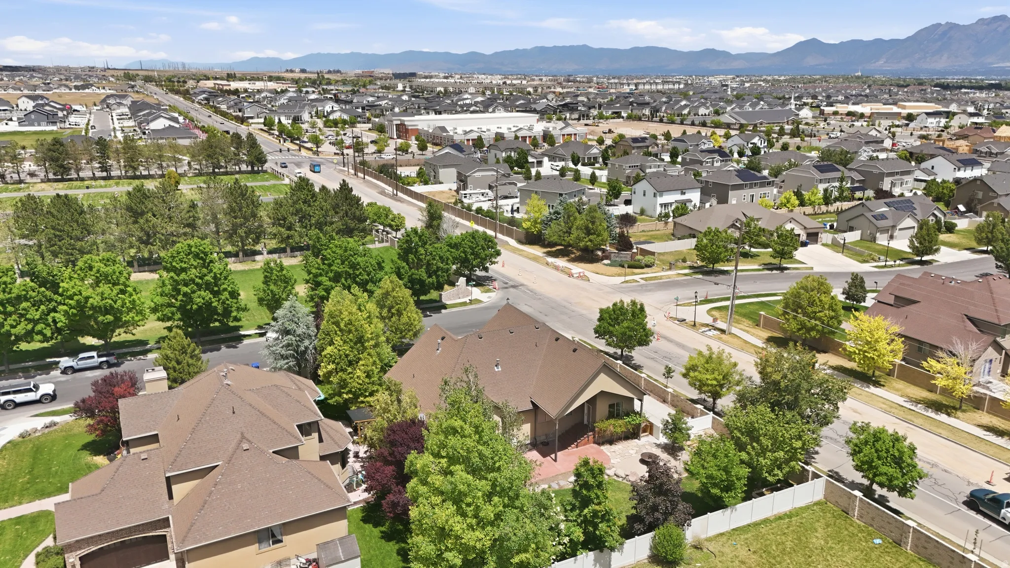Residential property featuring a neutral-toned exterior, a multi-pitched roof, and mature perimeter landscaping