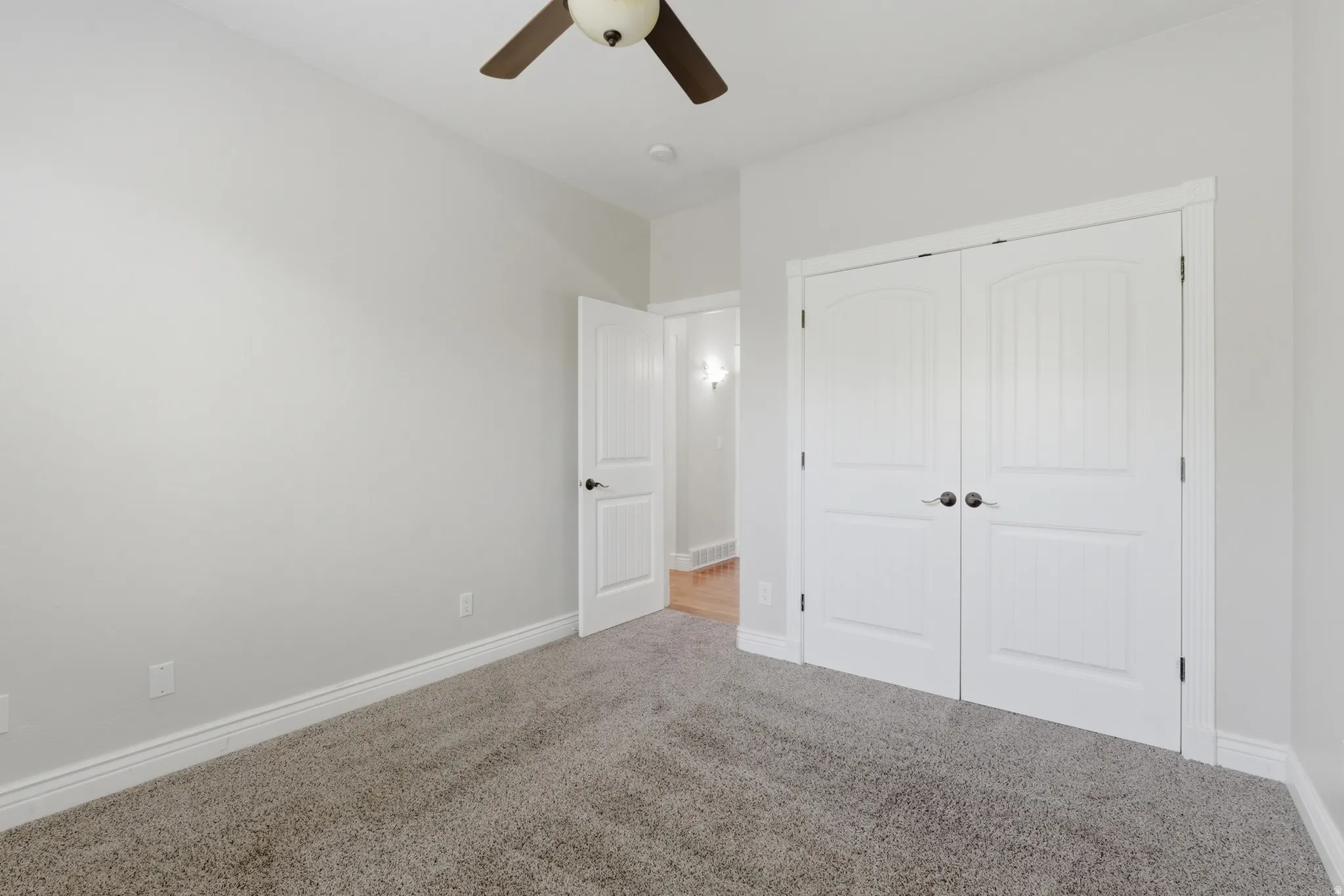 Room featuring neutral-toned carpet, white baseboards, and a ceiling fan