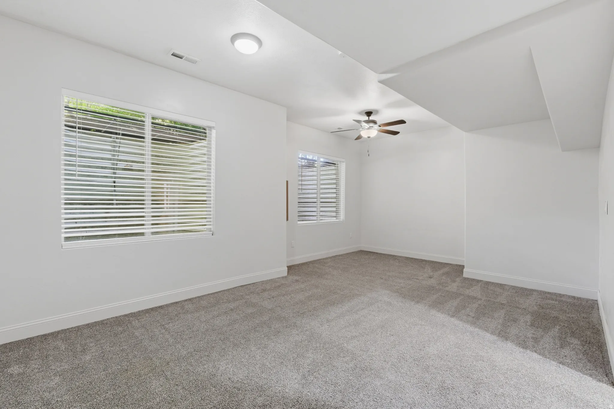 Spacious room featuring neutral carpeting and white walls