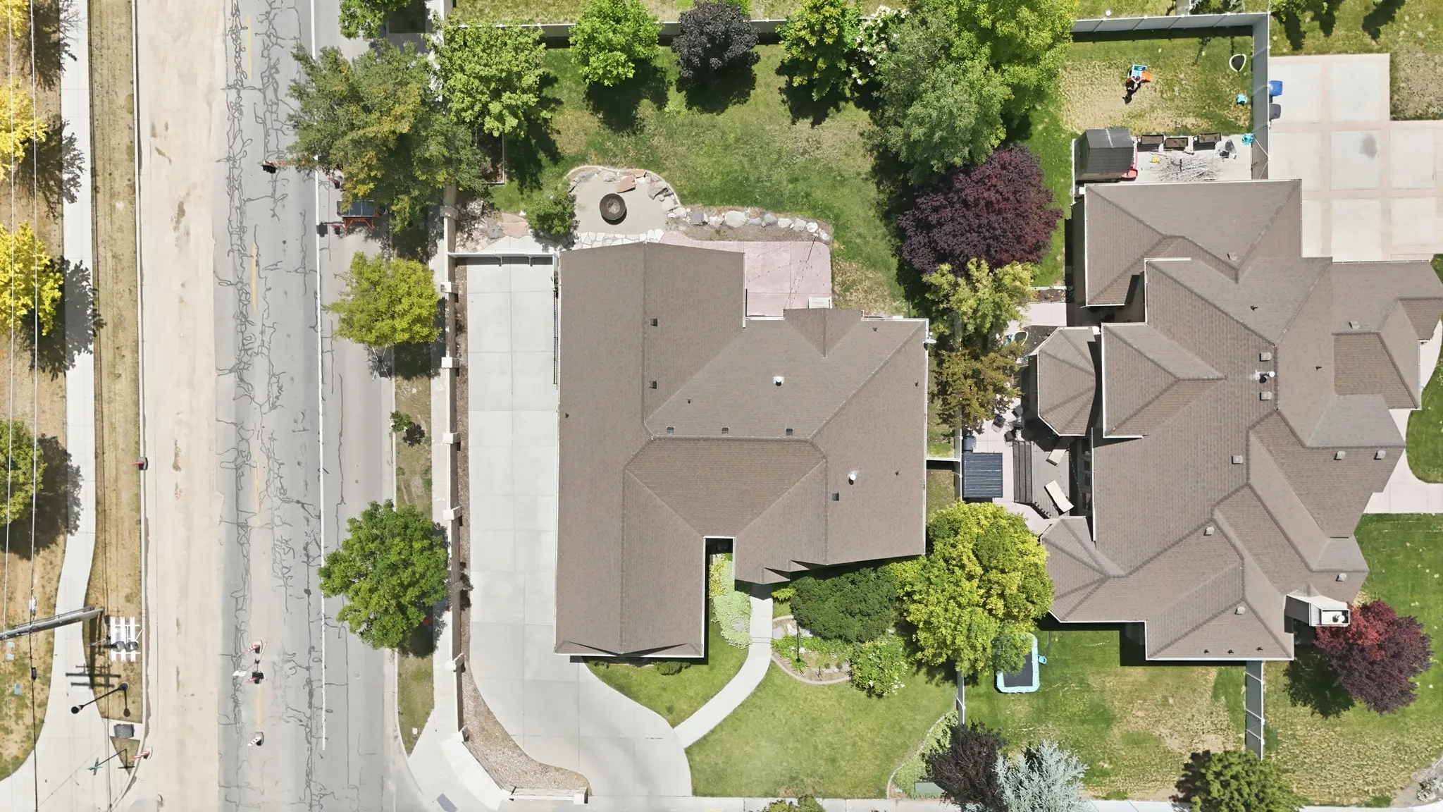Expansive property featuring a paved driveway, mature landscaping, and a multi-level roofline