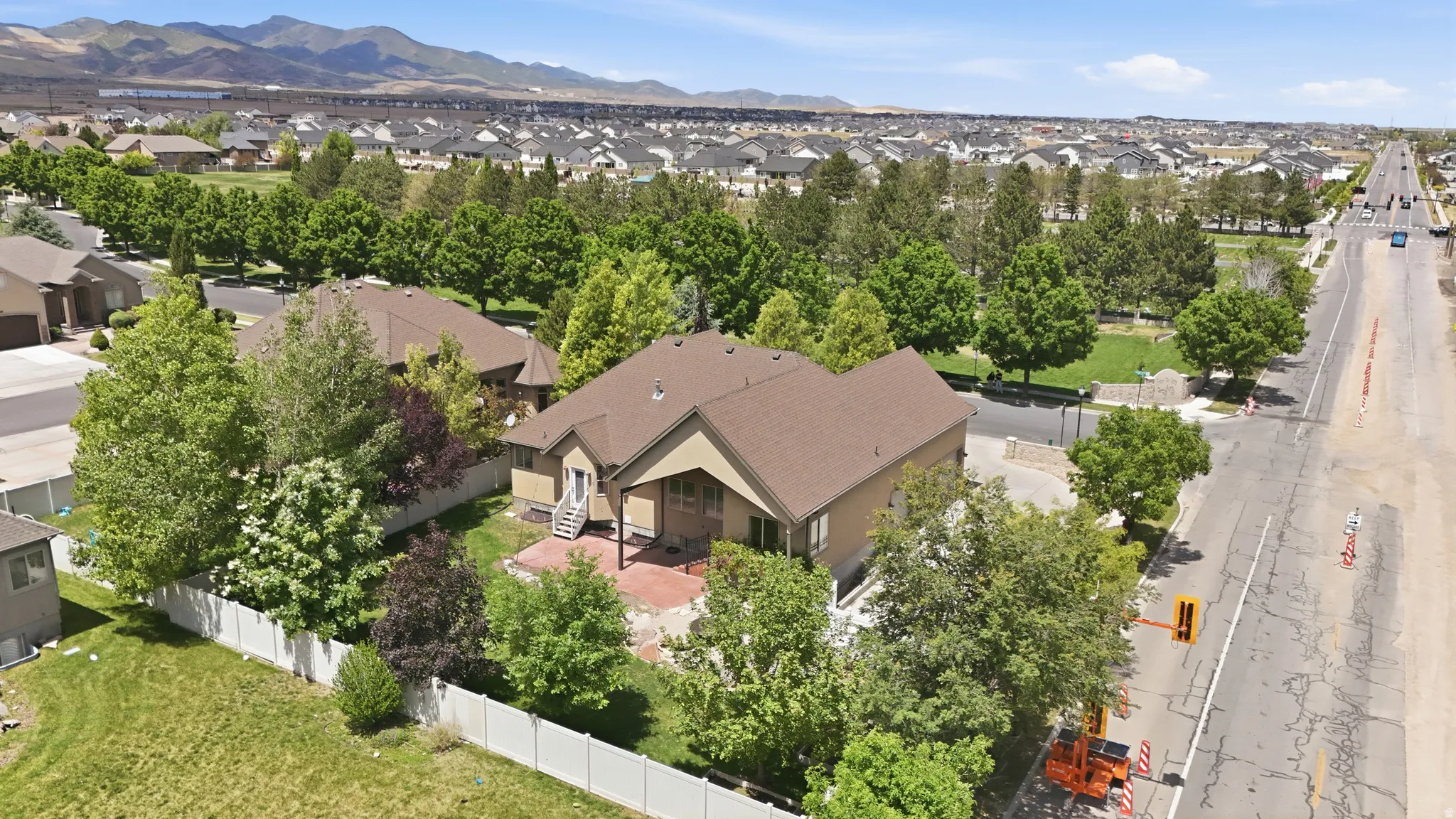 Tan exterior with brown roof, featuring a covered patio with stairs leading to a stone-paved area