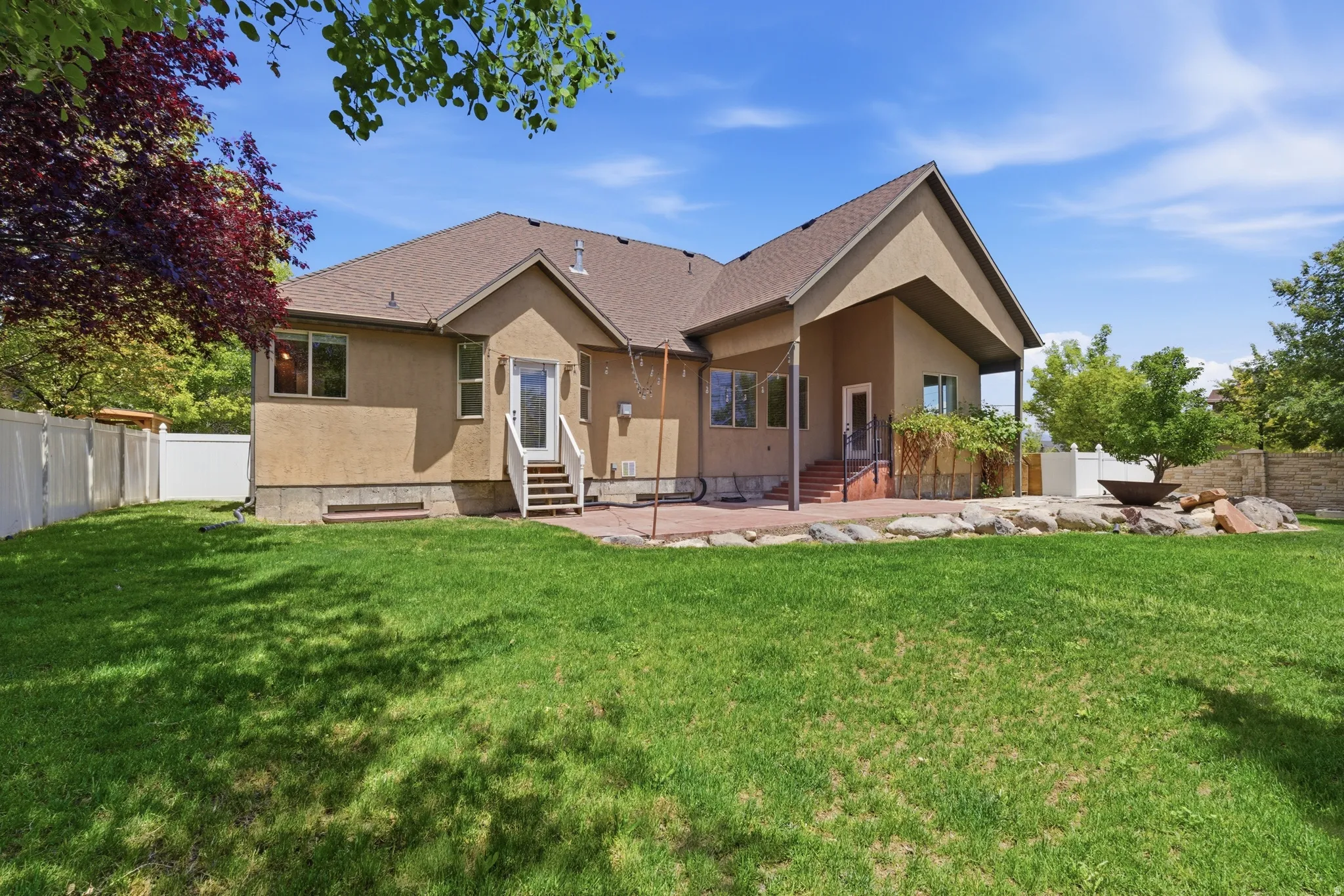 Expansive backyard featuring a manicured lawn, a white vinyl privacy fence, and mature trees