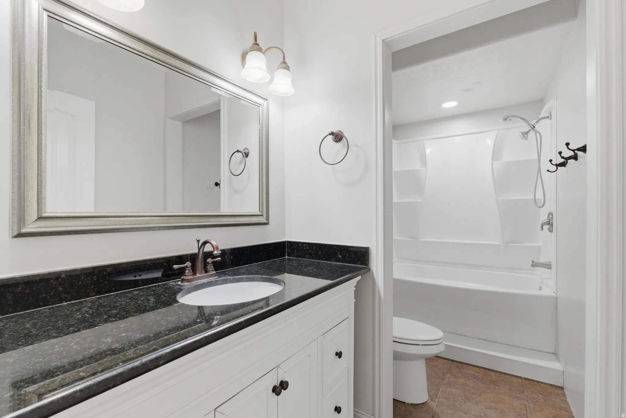 Bathroom vanity featuring an integrated sink, dark countertop, and brushed bronze faucet