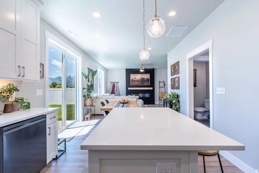 Open-concept kitchen featuring an expansive island with a light-colored countertop, white shaker cabinetry, and stainless steel appliances