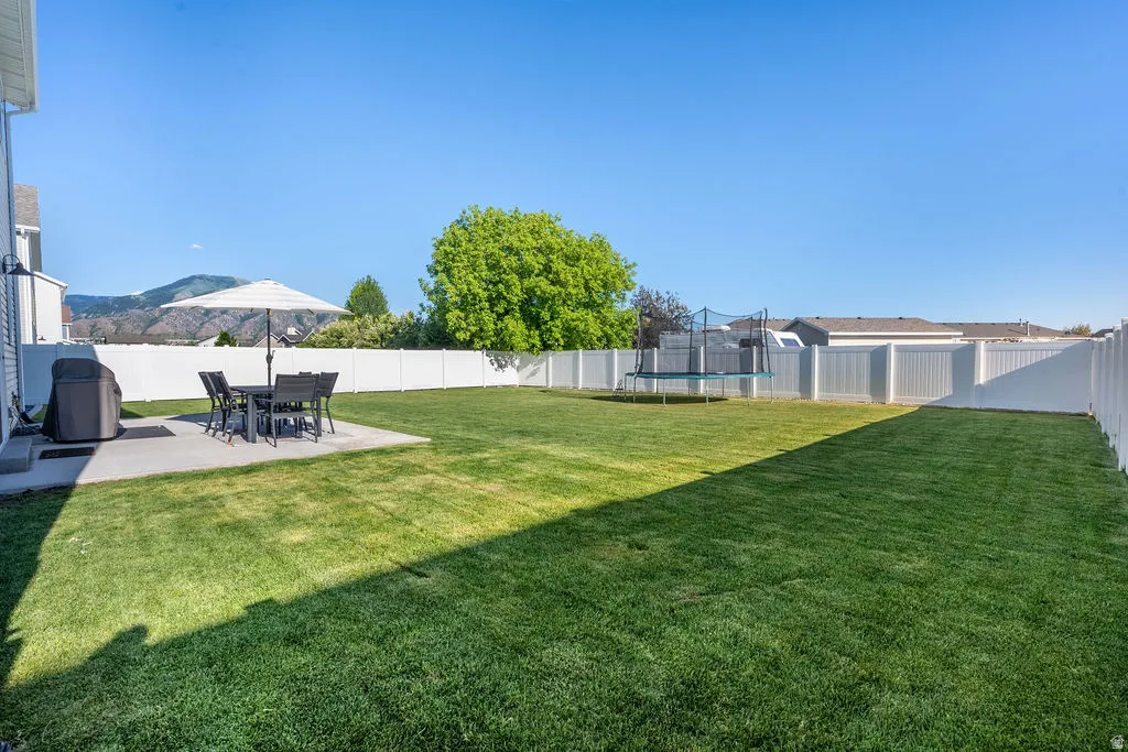 Expansive backyard featuring a large concrete patio, a vast lawn area, and full privacy fencing