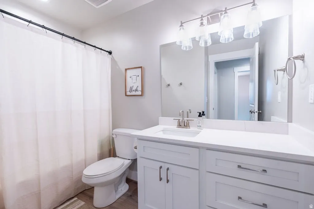 White vanity with integrated sink, brushed nickel faucet, large mirror, and light fixture featuring glass shades