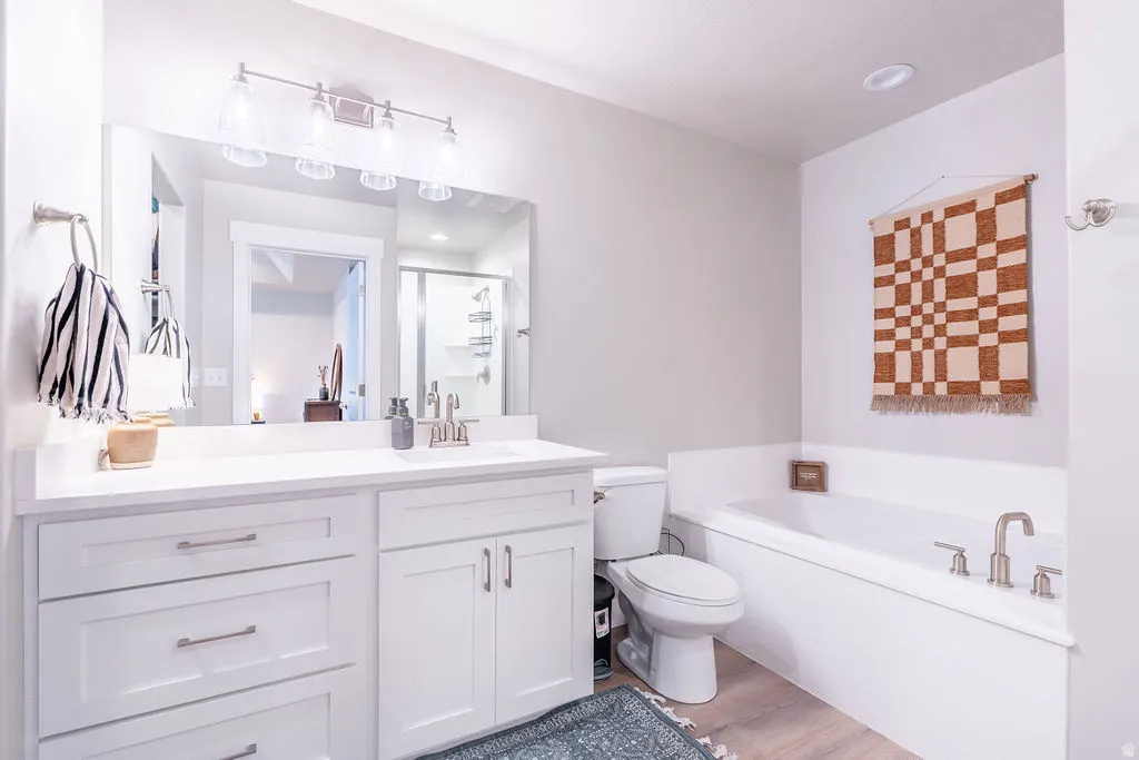 Bathroom featuring a soaking tub with brushed nickel fixtures, a white vanity with a single sink and brushed nickel faucet, a large frameless mirror, and recessed lighting