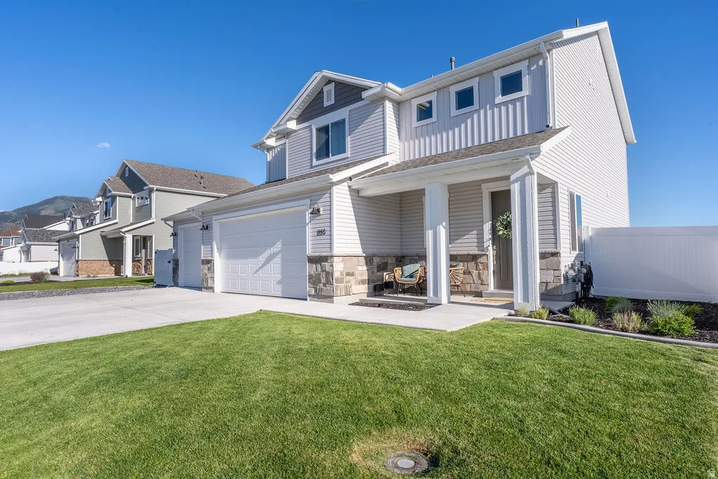 Contemporary two-story residence with a covered porch, stone veneer accents, and light-toned siding