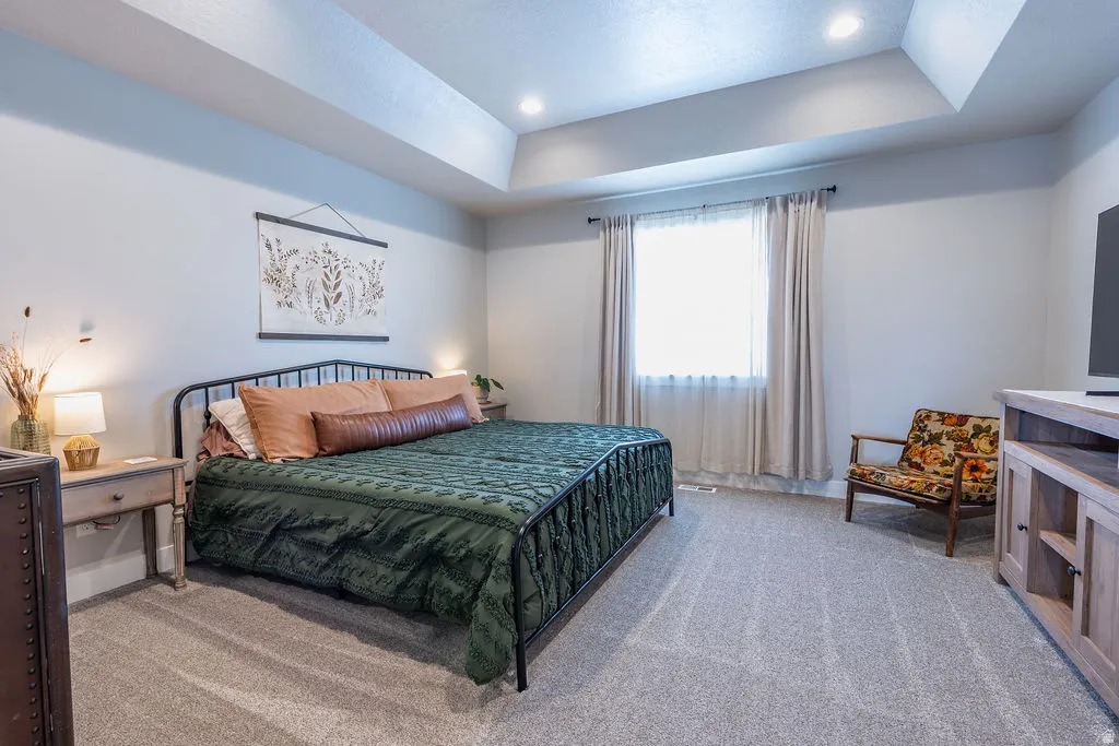 Spacious room featuring a tray ceiling with recessed lighting, light gray wall paint, and gray carpet flooring