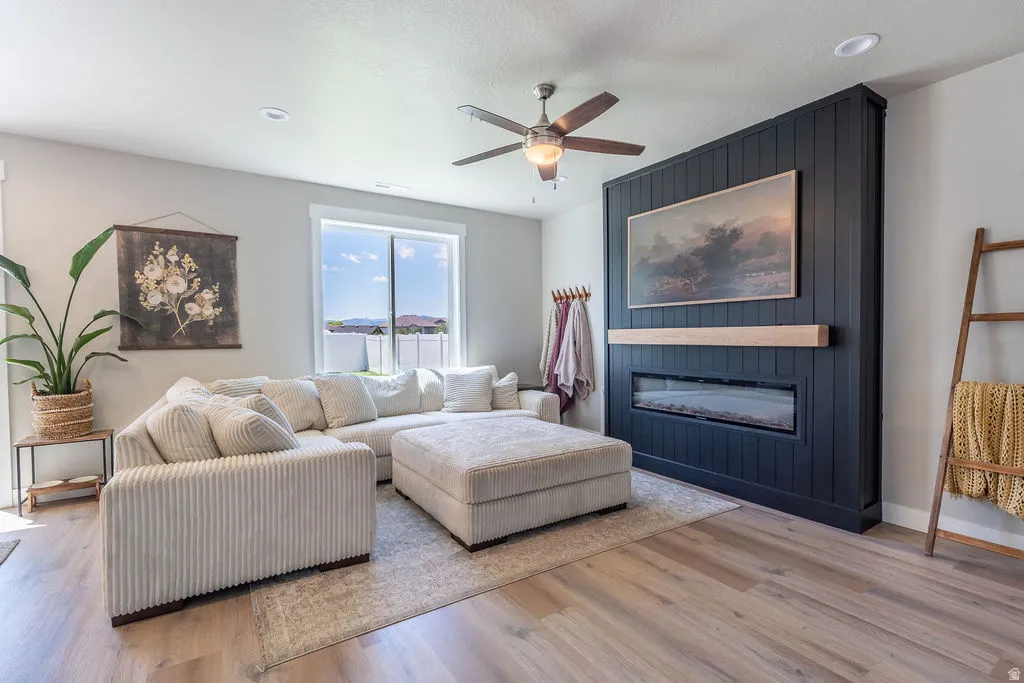 Living area featuring wood-finish flooring, a contemporary ceiling fan, and recessed lighting