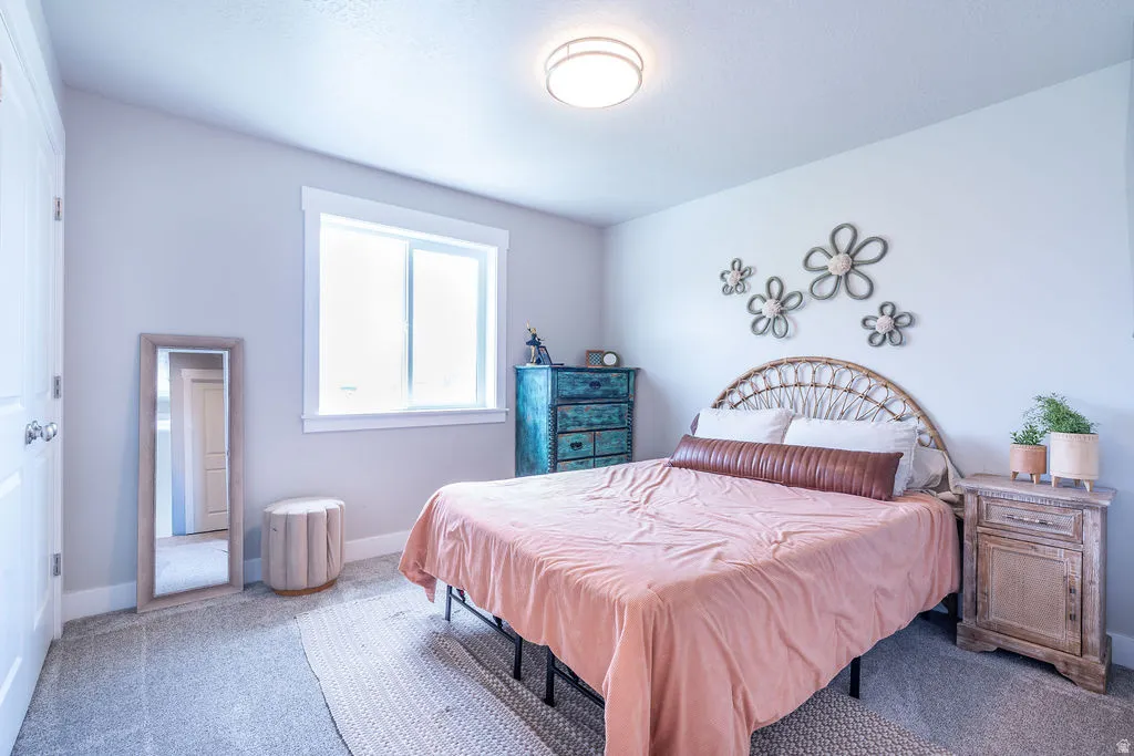 Bright bedroom featuring plush gray carpeting, a large window with white trim, and a contemporary ceiling light fixture