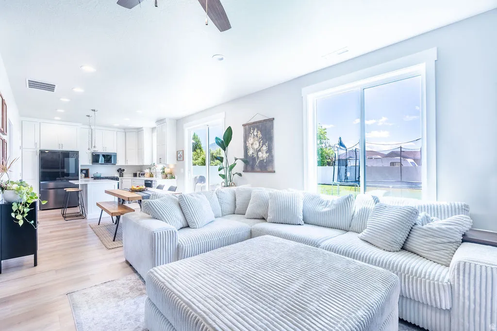 Open-concept living area featuring light wood-finish flooring, recessed lighting, and a ceiling fan