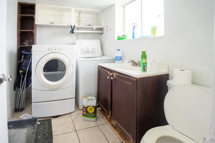 Compact utility space featuring a window, built-in shelving, a vanity with a sink, and tile flooring