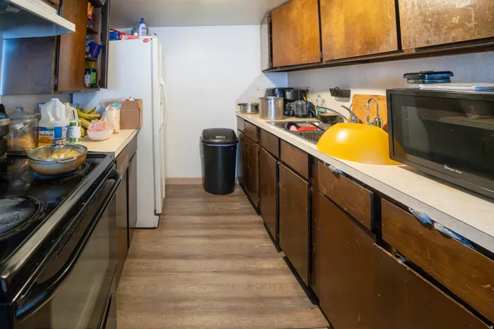 Galley kitchen featuring wood-finish flooring, white walls, and a white refrigerator