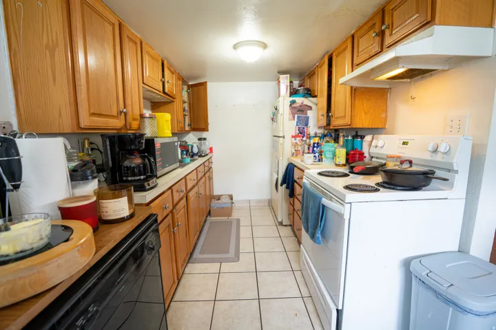 Kitchen featuring light wood cabinetry, white countertops, tile flooring, and a white electric range