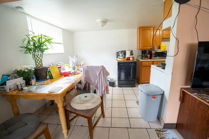 Kitchen area featuring tile flooring, light wood cabinetry, and a window with horizontal blinds