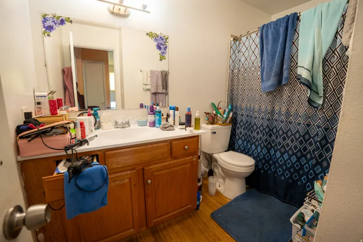 Bathroom featuring a wood-finish vanity with an integrated white sink, ample counter space, and an overhead vanity light