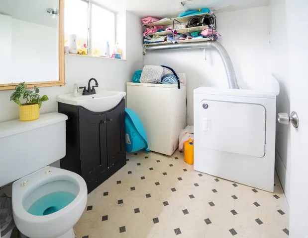 Compact utility space featuring a white toilet, black vanity with an integrated sink, and patterned floor tiles