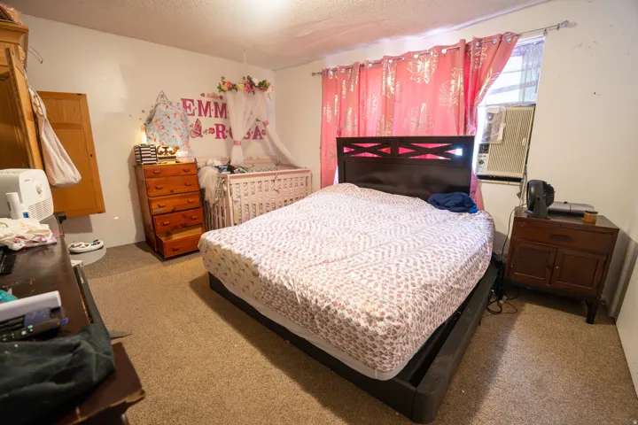 Carpeted interior space with a window-mounted air conditioning unit and a ceiling-mounted light fixture
