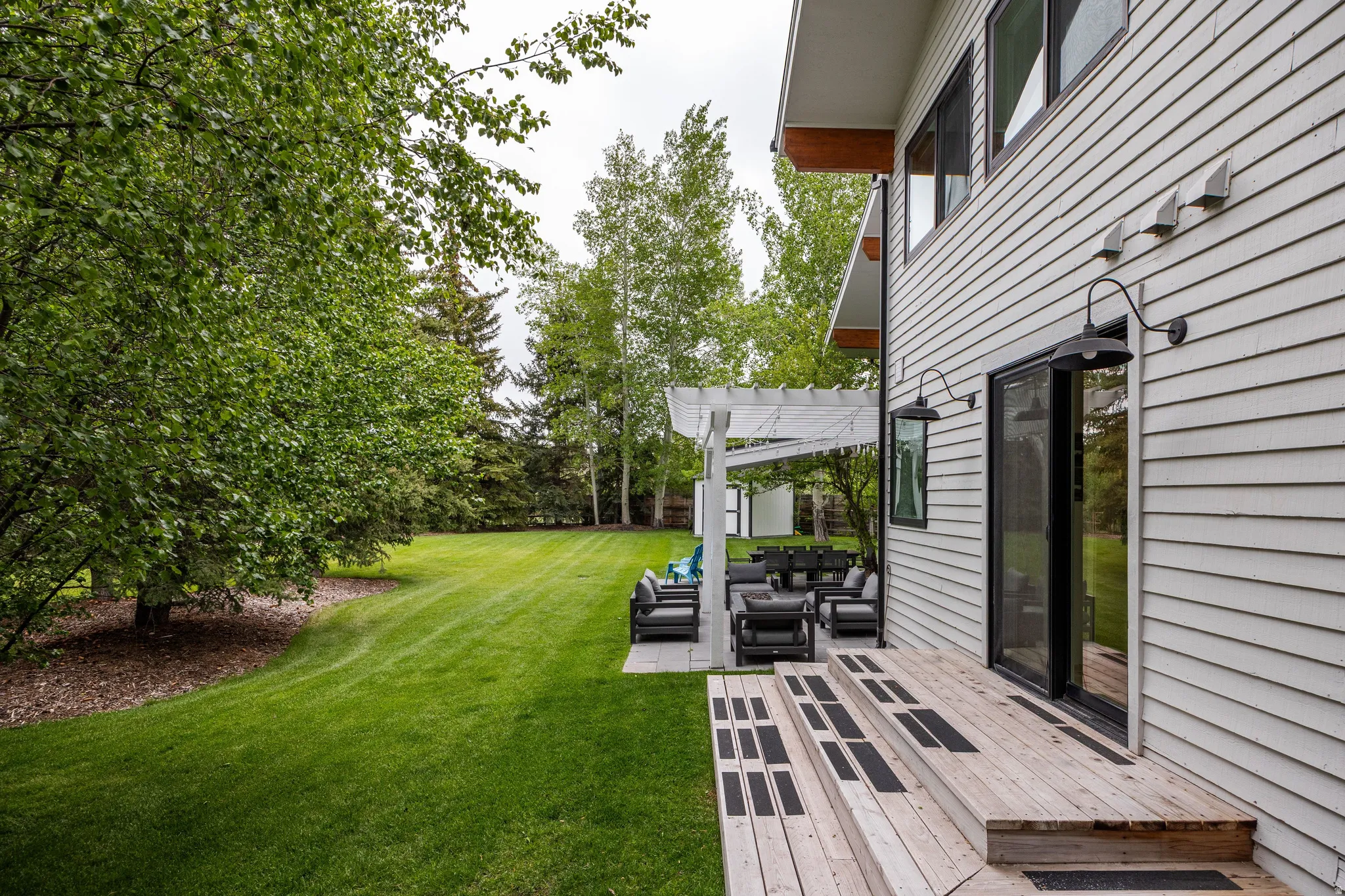 Expansive backyard featuring a manicured lawn, mature trees, and a multi-level wood deck
